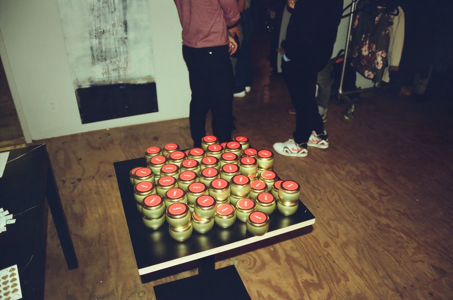 A black table with gold candle containers labeled “Merit." 