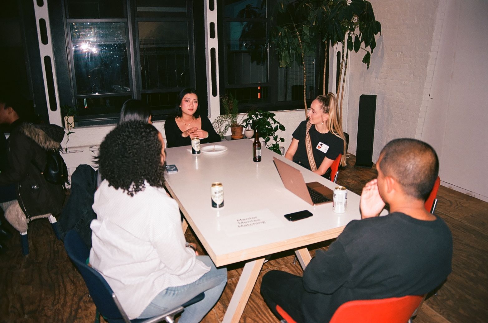 A group of five people sitting around at a table in a meeting space. 