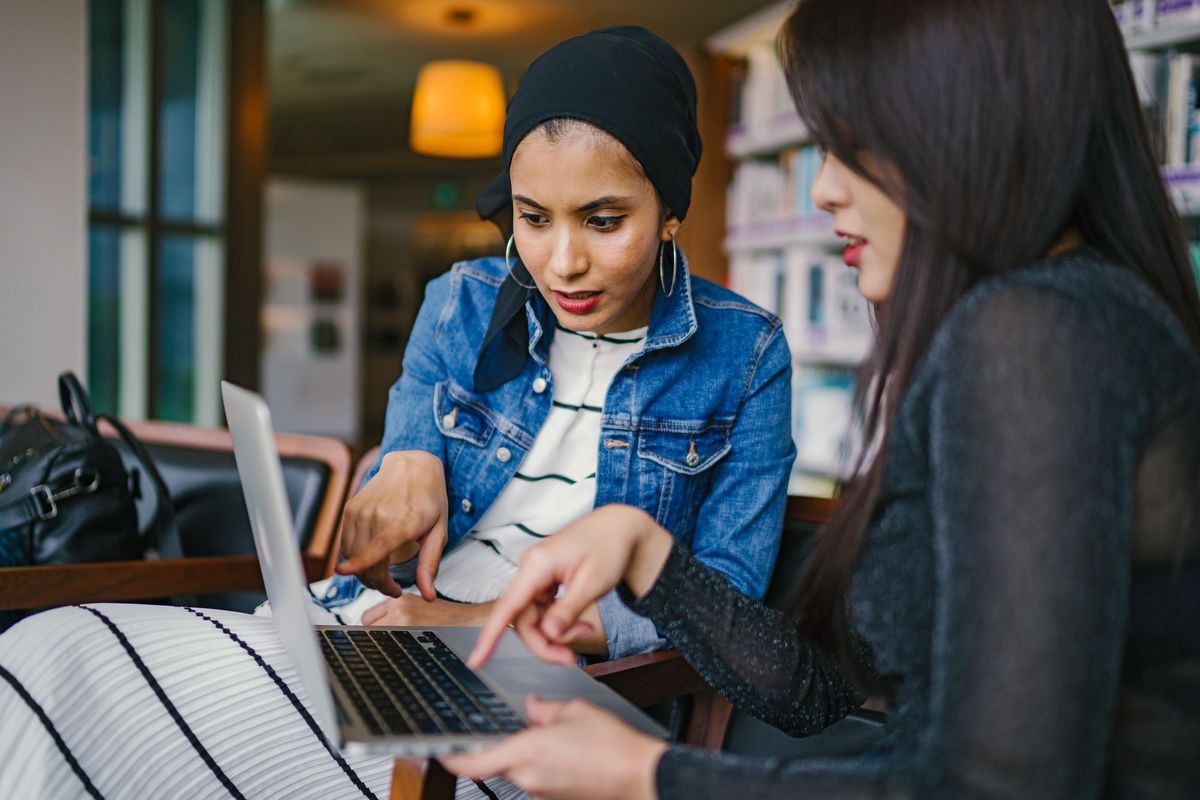 Two women pointing at a laptop screen